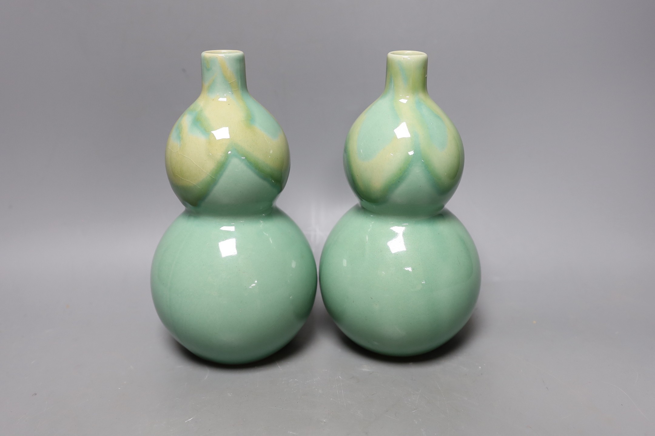 A pair of Chinese celadon ground bottle vases 21cm tall